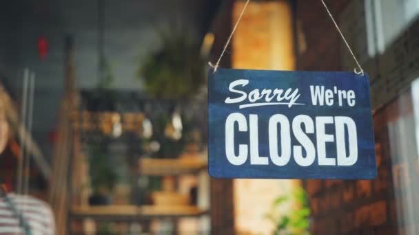 Cafe Manager wijzigen gesloten om te openen teken op venster glimlachend naar buiten — Stockvideo
