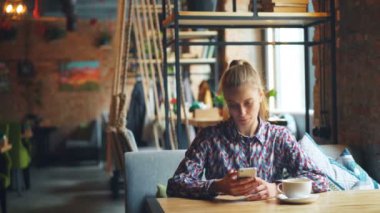 Kafede akıllı telefon kullanan kadın müşteri daha sonra gülümseyen garsonla konuşuyor