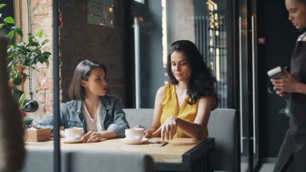 Meninas clientes café fazendo pagamento on-line com smartphone falando com garçonete — Vídeo de Stock