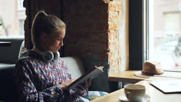 Mulher bonita desfrutando de livro engraçado no café lendo e rindo — Vídeo de Stock