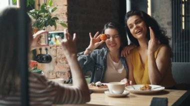 Kafede akıllı telefon kamerası için poz veren fotoğraf çeken çekici genç hanımlar