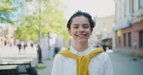 Portret van Happy Teenage Kid glimlachend kijken naar camera buitenshuis op zonnige dag — Stockvideo