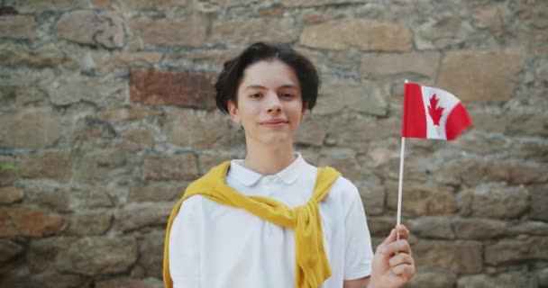 Retrato de adolescente canadiense sosteniendo la bandera de Canadá sonriendo mirando a la cámara — Vídeos de Stock