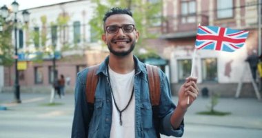 İngiliz bayrağı nı havada tutan yakışıklı Arap adamın yavaş hareketi