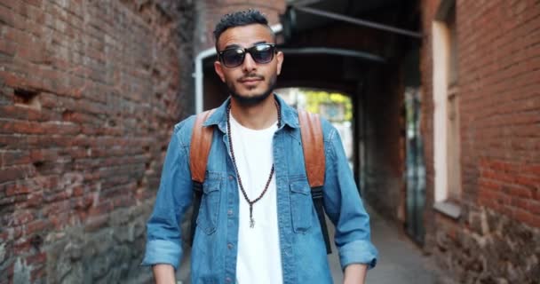 Mouvement lent de l'homme arabe attrayant décoller des lunettes de soleil souriant à l'extérieur — Video