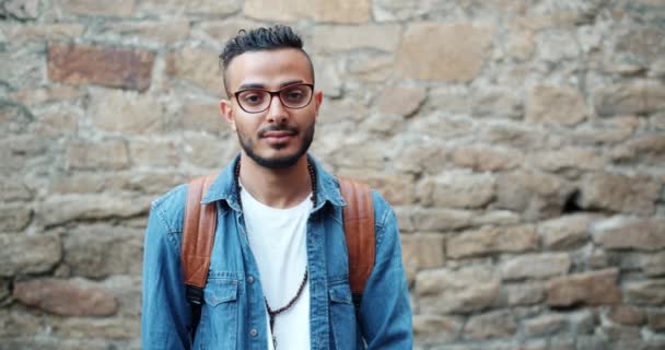 Cámara lenta de atractivo estudiante árabe sonriendo de pie al aire libre solo — Vídeo de stock