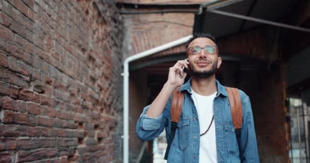 Счастливый арабский турист разговаривает по мобильному телефону смеясь стоя на улице — стоковое видео