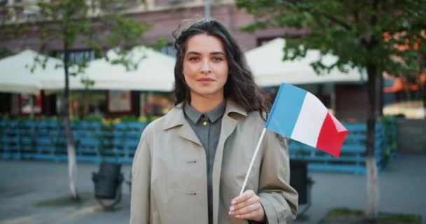 Retrato em câmera lenta da linda garota francesa de pé ao ar livre com a bandeira da França — Vídeo de Stock