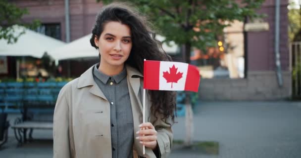 Portré csinos fiatal hölgy gazdaság kanadai zászló az utcán mosolygós — Stock videók