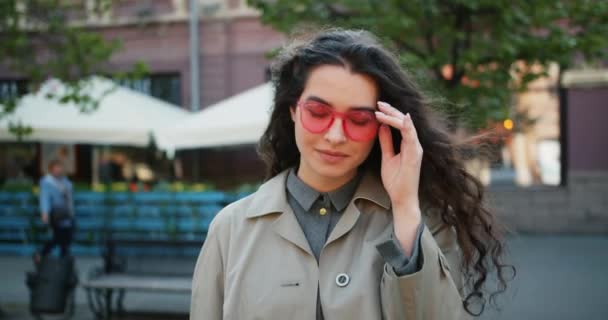 Porträtt av charmig ung dam tar av solglasögon och leende utomhus — Stockvideo