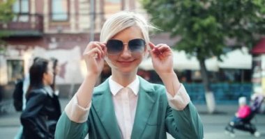 Sokakta gülümseyerek duran güneş gözlüğü çıkararak neşeli hipster yavaş hareket