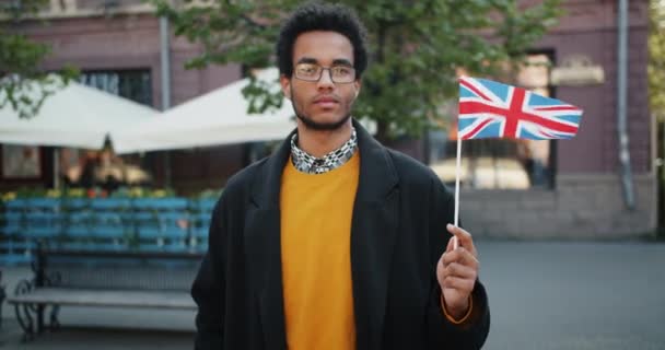Πορτραίτο της αφρικανικής αμερικανικής τουριστικής που κατέχει βρετανική σημαία στέκεται στο δρόμο — Αρχείο Βίντεο