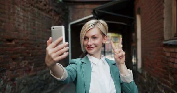 Slow Motion van mooie jonge vrouw die selfie buitenshuis neemt met smartphone — Stockvideo