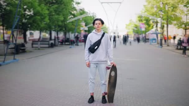Time-lapse of young boy standing alone in the street holding skateboard — Stock Video
