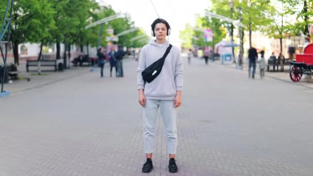Časový výpadek teenagerů ve sluchátkách naslouchající hudbě stojící na ulici — Stock video