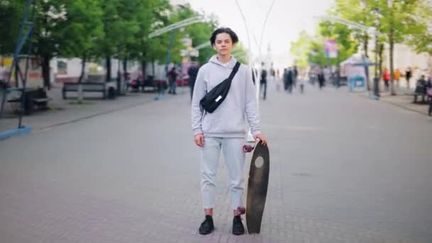 Zoom-in time-lapse de skatista de pé na rua com skate sozinho — Vídeo de Stock