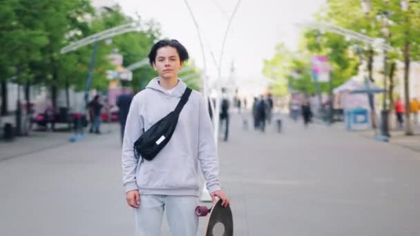 Проміжок часу портрет стильного підлітка скейтбордиста, що стоїть на вулиці один — стокове відео