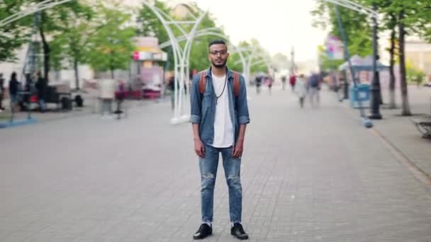 Zoom-in time lapse van Afro-Amerikaanse student staande in straat met rugzak — Stockvideo