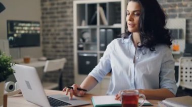 Dizüstü bilgisayarla çalışan ve ofiste not defterine yazan çekici kız