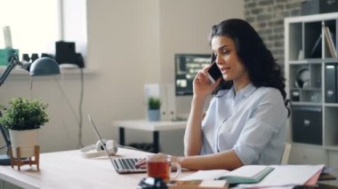Ofiste cep telefonu sohbet ve dizüstü bilgisayar kullanarak güzel kadın çalışan