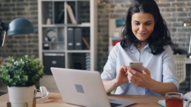 İş yerinde gadget ekranına dokunan akıllı telefon ile mesajlaşma güzel genç kadın