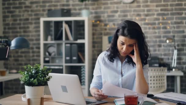 Office-werknemer lezen document vervolgens met behulp van laptop typen werken alleen binnenshuis — Stockvideo