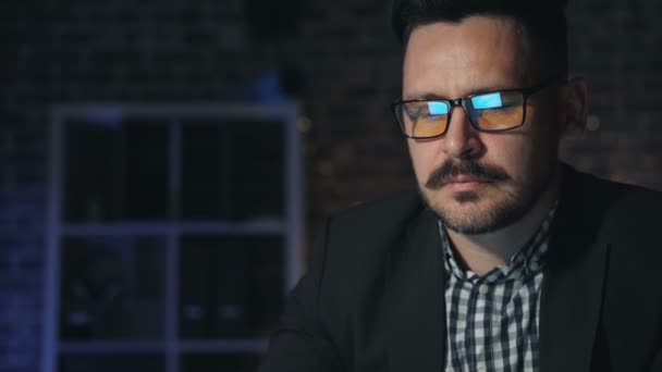 Portret przystojnego biznesmena w okularach pracujących z komputerem w ciemnym biurze — Wideo stockowe