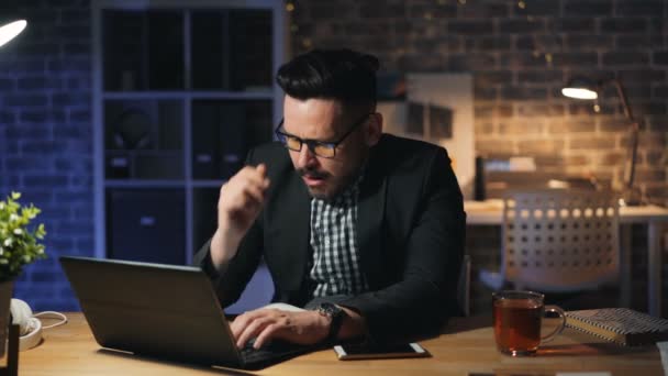 Porträt eines erschöpften Unternehmers, der gähnend mit Laptop im dunklen Büro arbeitet — Stockvideo