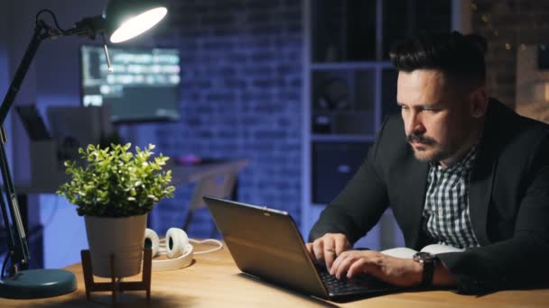프로젝트로 바쁜 사무실에서 밤에 초과 근무를 하는 노트북을 사용하는 남성 직원 — 비디오