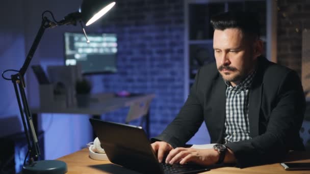 Gelukkig kantoorwerk nemer afwerking werk met laptop 's nachts zittend in stoel glimlachend — Stockvideo