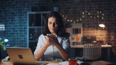 Akıllı telefon kullanan genç bayan gece fazla mesai konuşma ekran dokunmadan