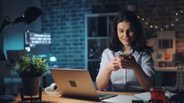 Pretty kız gece ofiste çalışan akıllı telefon kayıt sesli mesaj kullanarak