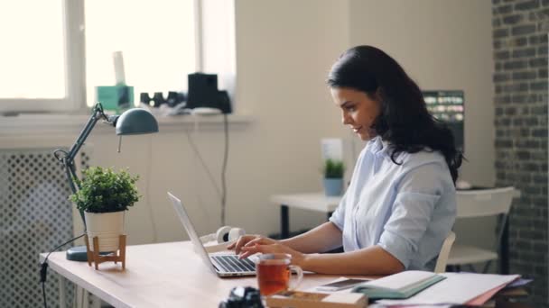 Успешная деловая женщина работает с ноутбуком, а затем расслабляется улыбаясь, чувствуя себя счастливой — стоковое видео