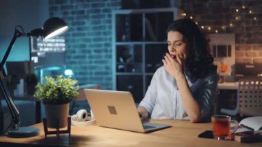 Yorgun ofis çalışanı bilgisayar kullanarak ve tek başına gece geç saatlerde çalışan esneme