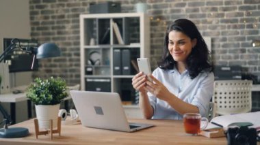 Ofiste akıllı telefon ile online görüntülü görüşme yapan duygusal genç kadın
