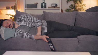 Tv uzaktan kumandatutan tek başına kanepede uyuyan yorgun kişinin portresi
