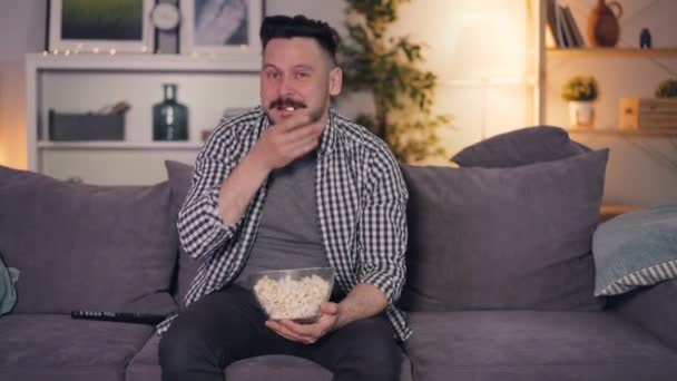 Fröhliche Person, die Show im Fernsehen sieht, lacht und zeigt auf Bildschirm, der Popcorn isst — Stockvideo