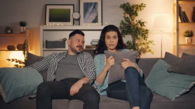 Evde kanepede oturan Tv'de korkunç korku filmi izlerken güzel çift
