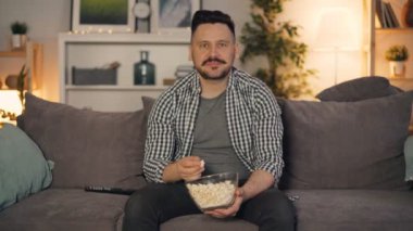 Orta yaşlı adam tv izlerken patlamış mısır yeme ve evde film zevk gülümseyerek