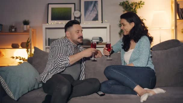 Mann und Frau beim Gläserklirren und Wein trinken zu Hause auf dem Sofa — Stockvideo