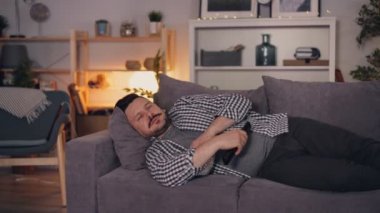 Evde tek başına kanepede yatan patlamış mısır yiyen Tv izlerken Uykulu kişi adam