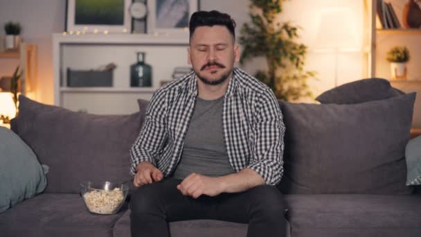 Guy guardando il programma televisivo a casa mangiare popcorn gesticolando e parlando — Video Stock