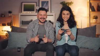 Gece geç saatlerde eğlenen neşeli gençler evde video oyunları oynuyor