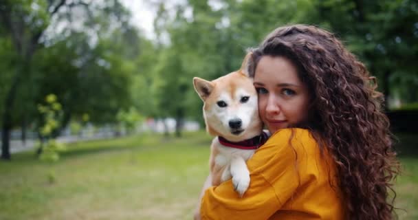 Retrato de una joven feliz sosteniendo un hermoso cachorro en el parque en verano — Vídeos de Stock