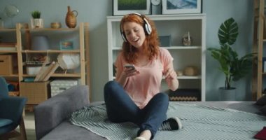 Evde akıllı telefon dansı kullanarak kulaklıkla müzik dinleyen kız