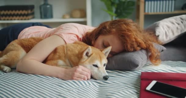 Attractive young woman and cute dog sleeping together at home on bed hugging — Stock Video