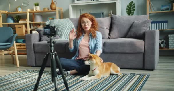 Симпатичный блогер-подросток, записывающий видеоблог, сидящий дома на полу с собакой — стоковое видео