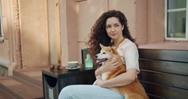 Sevimli kız öğrenci stroking sevimli shiba inu köpek bankta açık havada oturan