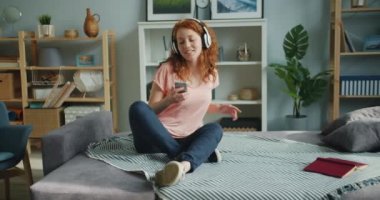Sevimli kız müzik dans dinleme ve evde akıllı telefon kullanarak yavaş hareket