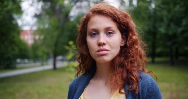 Retrato de niña estudiante sonriendo mirando a la cámara en el parque verde en el día de verano — Vídeo de stock